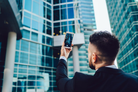 Businessman taking photo of office building on phone