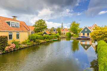 Fototapeta na wymiar Yndyk, Hindeloopen, province of Friesland, municipality Súdwest-Fryslân, Netherlands, september 3, 2017: View to houses and boats at canal Yndyk seen from bridge at Nieuwe Weide