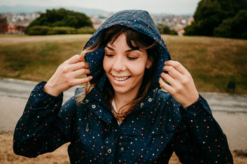 .Young woman enjoying a rainy day in the north of spain with her blue raincoat with colored polka dots