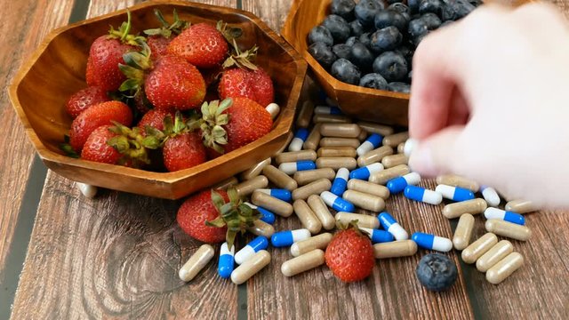fresh natural fruits vs pills. Natural vitamin in fruits vs synthetic vitamin in pills. Choice between natural and synthetic way of health care. Alternative medicine. Dietary supplement