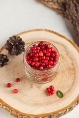 Fresh ripe cranberries in a transparent glass jar on a wooden stand. Autumn, useful berries. Harvest. Copy space.