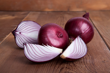 Red onion on the wooden background.