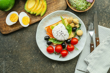 Plate with tasty avocado and egg sandwich on dark background