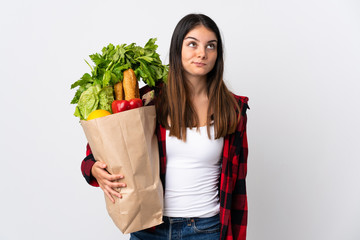 Young caucasian with vegetables isolated on white background and looking up