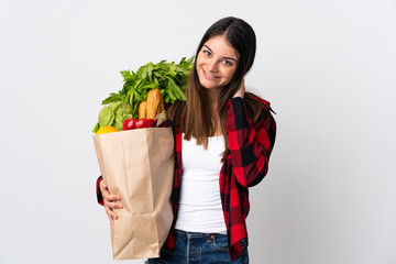 Young caucasian with vegetables isolated on white background laughing
