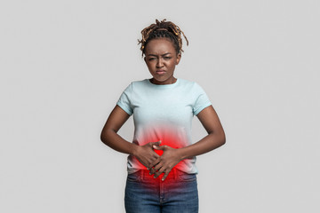 Young african woman suffering during menstruation, rubbing belly