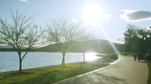 Static view of Lake Burley Griffin and Telstra Tower, with walkers passing by
