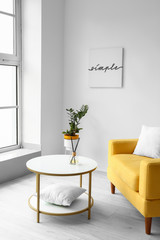 Stylish interior of living room with table and armchair