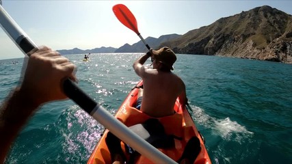 Sportsman kayaking in beautiful landscape at El Portús, Cartagena, Spain. Kayakers in double kayak practicing sport. Aquatic sports during summer concept.