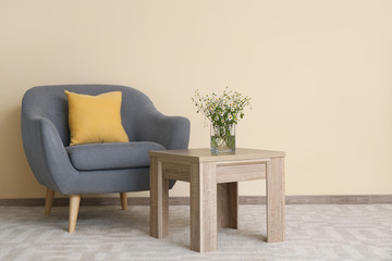 Stylish interior of living room with table and armchair