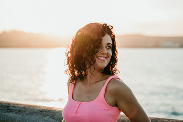 .Young curly-haired woman enjoying a summer sunset strolling through the fishing port in Gijón, northern Spain. Lifestyle