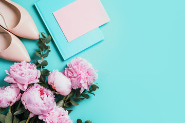 Beige women shoes nude shoes, pink peonies, eucalyptus flower on blue background. Flat lay, top view. Copy space. Floral mock up. Wedding, birthday, anniversary bouquet. Woman day, Mother's day