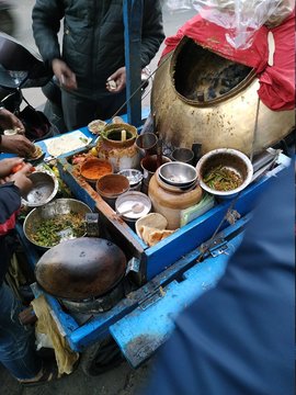 top view of people eating delicious spicy chole kulche /tangy spicy chickpea curry with bread tossed in butter street food at a public stall in a local market.