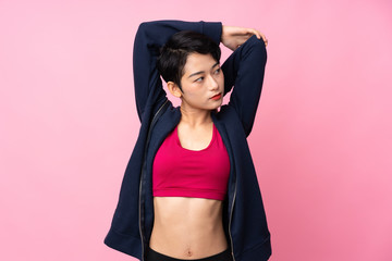 Young sport Asian woman over isolated pink background stretching