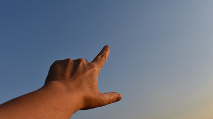 Hand einer Frau mittleren Alters zeigt mit Zeigefinger, zeigende Hand vor blauem Himmel