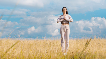 Fototapeta premium Young nice woman doing yoga in yellow field. Care concept