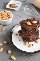 Brownie cake with almond nuts on on concrete background. Traditional chocolate dessert