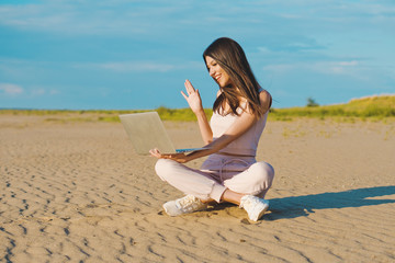 Nice woman in rose tracksuit conducting a video conference on the beach.