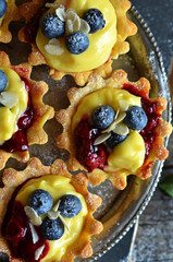 Tartlets with pudding and blueberries on a metal tray