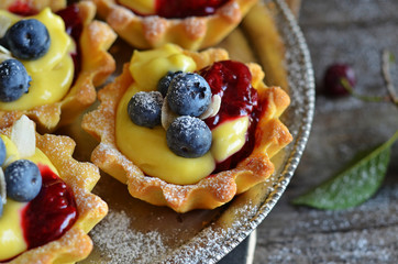 Mini tarts with pudding cream and blueberries on a rustic tray