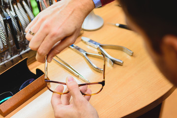 Closeup of male optician's hands repairing eyeglasses