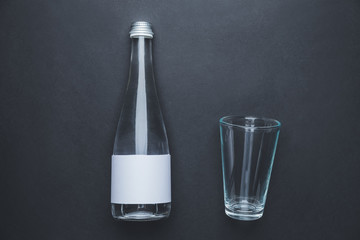 Bottle of clean water and glass on dark background