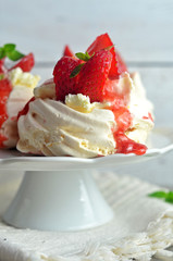 Meringue with strawberries on a light wooden background