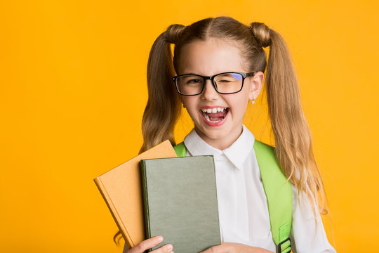 Funny School Girl Winking At Camera Holding Books In Studio