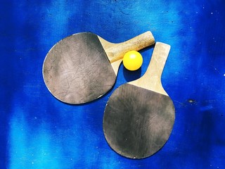 Two rackets and an orange table tennis ball.