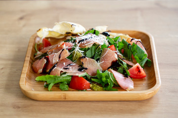 Fresh salad with tomatoes, arugula and bacon, sprinkled with parmesan cheese.