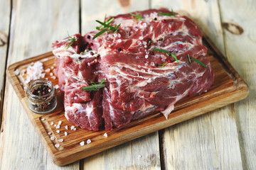 Selective focus. Raw meat on a board with salt and spices. Pork neck.