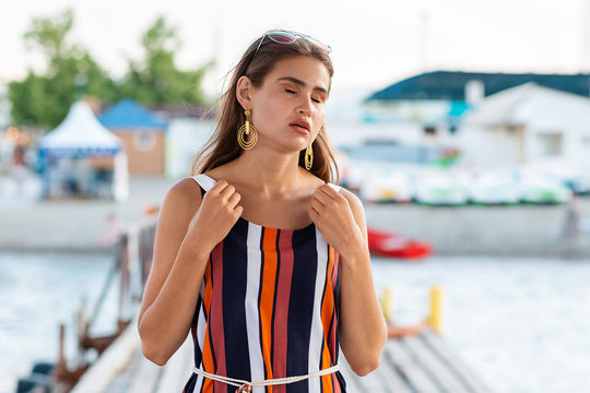 Summer. A tired woman holds on to the straps of her dress as she experiences heat stroke or faints. Concept of sunstroke and illness