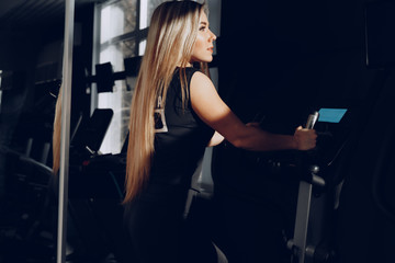 Obraz na płótnie Canvas Attractive young blonde woman exercising on cardio training apparatus