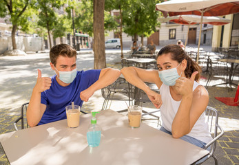 Couple with surgical face mask having coffee and greeting in the new elbow style in the New Normal