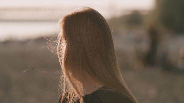 Face of young beautiful woman on the beach during amazing sunset who is turing right.