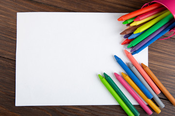 Obraz premium colored crayons and blank page on the wooden table