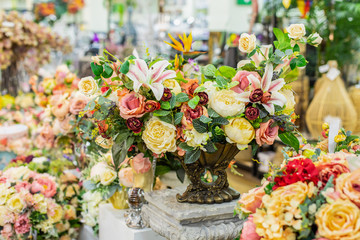 Home decor with artificial flowers, rose lily leaves. Elegant bouquet for home decor, yellow rose in a dark metal vase. Interior decoration, postcard design