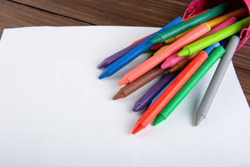 colored crayons and blank page on the wooden table