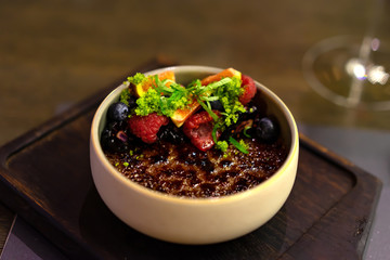 creme brulee with caramelized sugar custard decorated with berries and mint