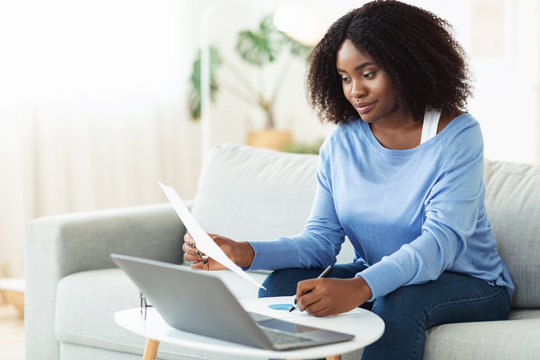 Black Woman Signing Papers Working On Laptop At Home
