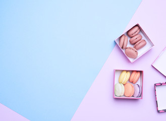 baked round multicolored macarons in square boxes on a colored pastel background