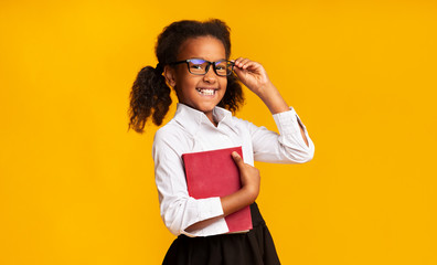 Cheerful Schoolgirl Holding Book Smiling To Camera Standing In Studio