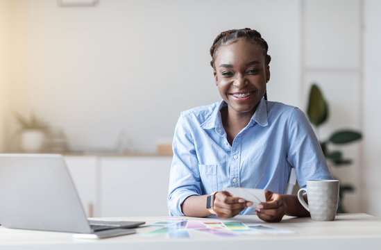 Black Interior Designer Woman Sitting At Desk With Color Swatches In Office