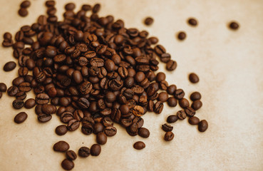 Coffee bean background. Dark-colored roasted coffee beans scattered on Kraft paper.