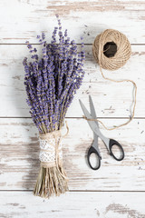 Beautiful dried lavender flowers bunch top view on white wooden background.