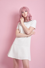 Beautiful girl with pink hair, hair coloring. Cute anime woman stands on a pink background in a short white dress. Colored hair, perfect hairstyle