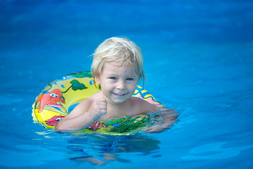 Fototapeta na wymiar Cute toddler boy, swimming in pool with board