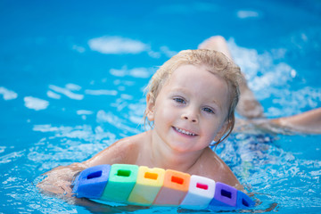 Cute toddler boy, swimming in pool with board