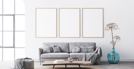 Frame mockup in interior living room design. Three vertical frames on white background with big window. modern grey sofa with plaid on, blue vase, and natural wooden table. Scandinavian home decor