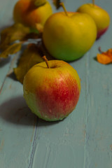 Four fresh apples with leaves lie on a wooden background